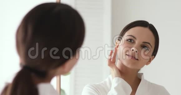 自信美丽的年轻女人把面霜照镜子视频的预览图