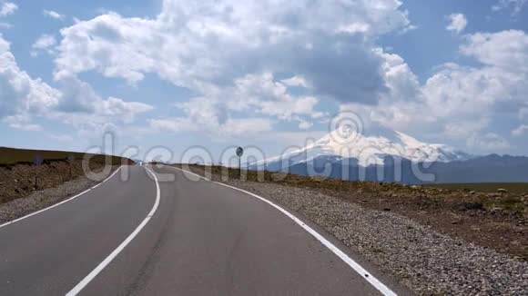 穿着短裤和t恤的家伙光着脚在空无一人的高速公路上奔跑背景是美丽的云和山埃尔布鲁斯视频的预览图