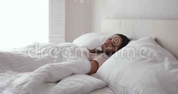 快乐的年轻女人在舒适的床上醒来视频的预览图