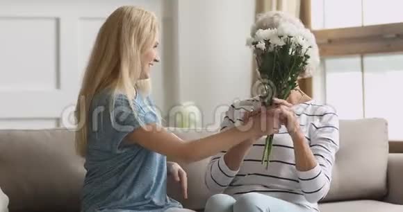 微笑的年轻女子送花给快乐的中年母亲视频的预览图