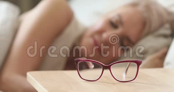 年长的成熟女人从床头柜里拿着光学眼镜视频的预览图