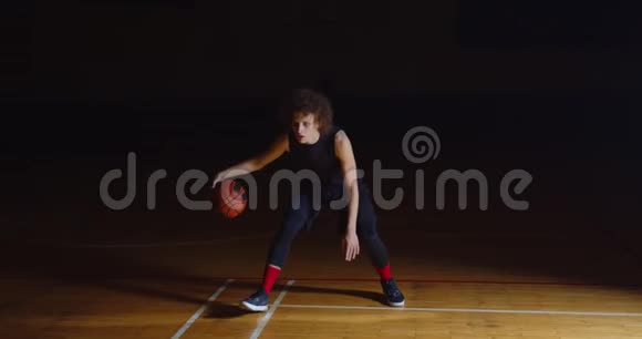 好奇的白种人篮球运动员运球镜头职业黑暗光线视频的预览图