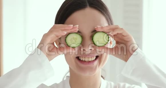 有趣的年轻女人用黄瓜遮住眼睛特写肖像视频的预览图