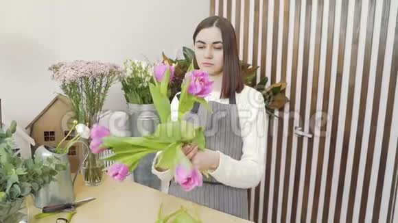 年轻女子花商在一家花店或作坊里创作一束郁金香视频的预览图
