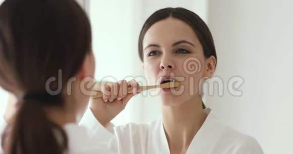 幸福的女人拿着木制牙刷刷牙照镜子视频的预览图