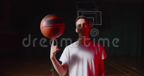 特写白种人青年篮球运动员肖像红光光束黑色暗篮背景与球视频的预览图