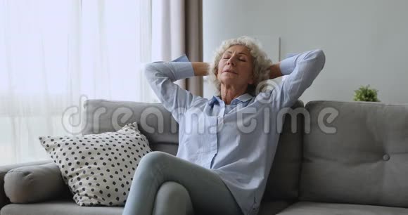 平静的年长成熟的女士在舒适的沙发上放松视频的预览图