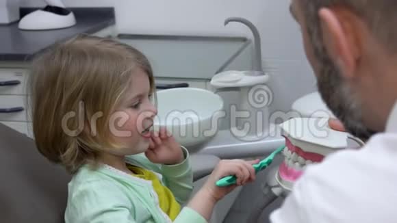一个可爱的小女孩正在训练她在下巴模型上清洁牙齿视频的预览图