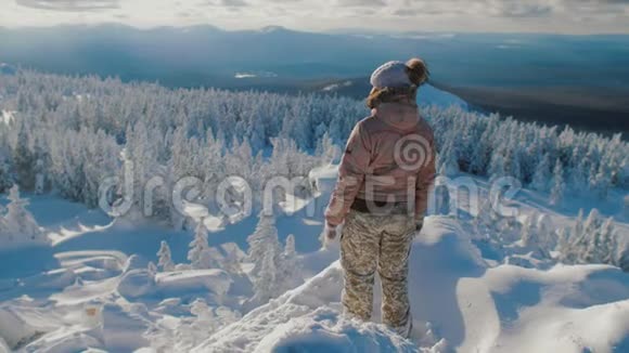 女子徒步旅行者站在雪山之上欣赏风景视频的预览图