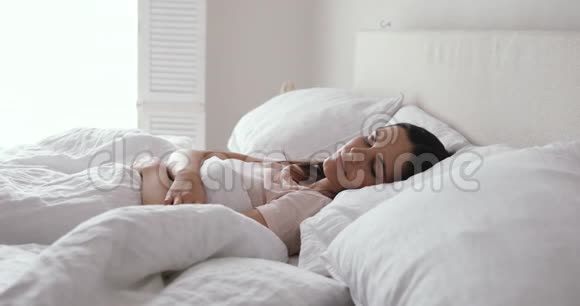 一个人在舒适的床上醒来的年轻女子快乐而有意识视频的预览图