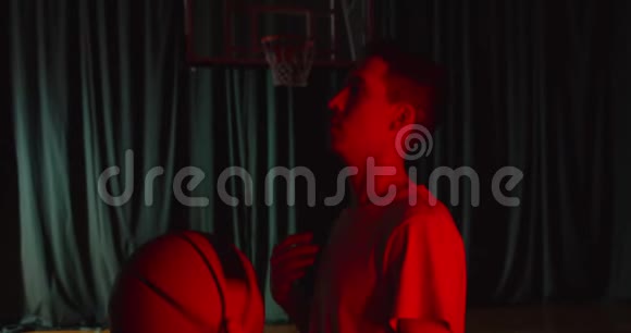 一位白人篮球运动员在自信的背景下举着一个红灯篮球的年轻肖像热身视频的预览图