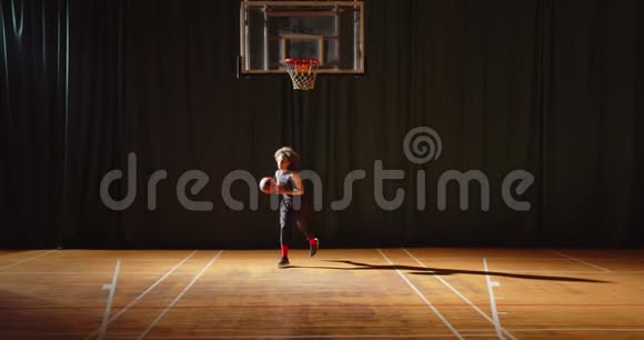 年轻的卷曲篮球运动员玩球拍把球扔进篮子夜间黑暗训练训练视频的预览图