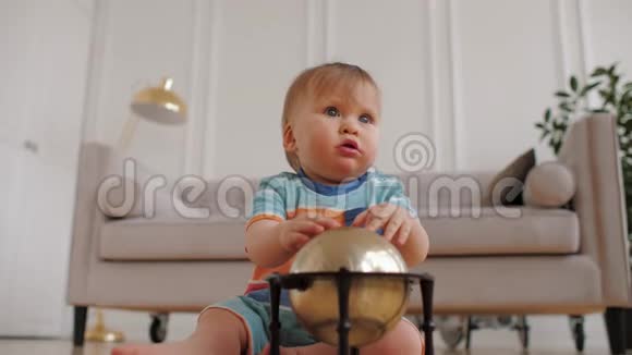可爱的小男孩蓝眼睛坐在家里的地板上玩玩具地球仪视频的预览图