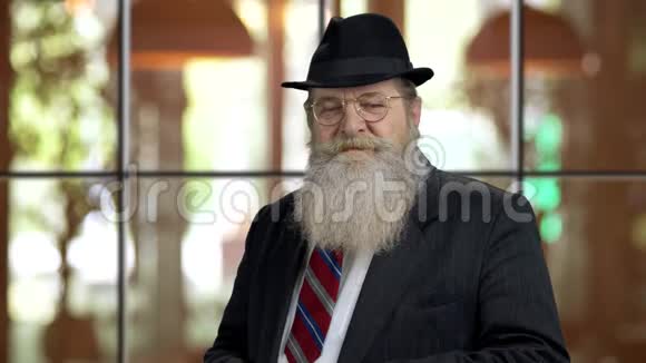 戴黑色西装和帽子的大胡子老人的肖像视频的预览图