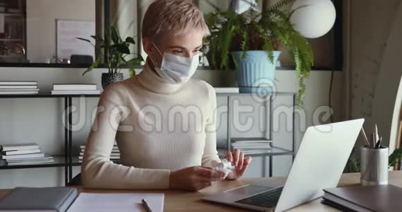 女商人戴着医用口罩清洁手提电脑键盘和消毒液视频的预览图