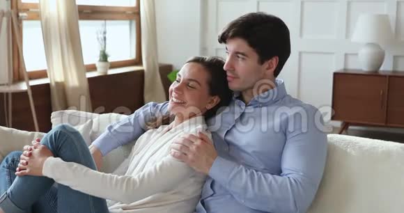 一对浪漫的年轻夫妇在家里的沙发上闲荡视频的预览图