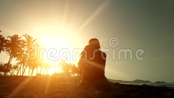 一个快乐女孩的剪影在日落时抛出沙子幸福和好运的概念视频的预览图