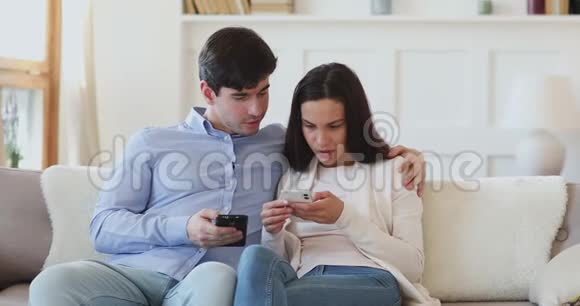 年轻夫妇用两部手机聊天在沙发上放松视频的预览图