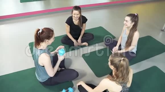 一群年轻的女性在锻炼后坐在健身房的地板上谈笑风生视频的预览图