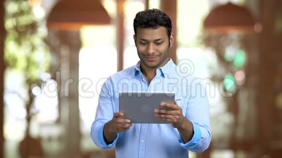棕色皮肤的男人拿着平板电脑和网上的人打招呼视频的预览图