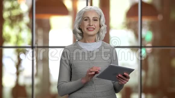 积极有吸引力的老太太拿着平板电脑说话视频的预览图