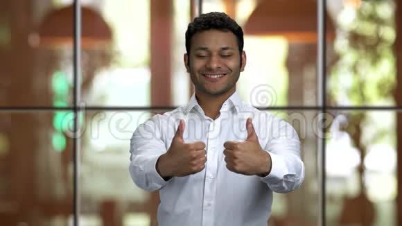 一位年轻的印度教男子的画像他身穿白色衬衫竖起大拇指视频的预览图