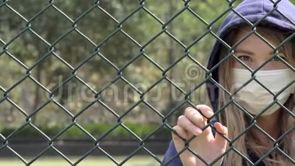 关闭边界检疫年轻女子的特写戴着护面面具站在栅栏的边界后面COVID19视频的预览图