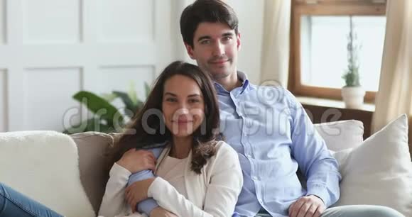 幸福的年轻夫妇拥抱在沙发上放松看着相机视频的预览图