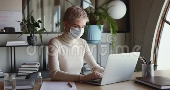 戴口罩和医用手套的女商人在手提电脑上工作视频的预览图