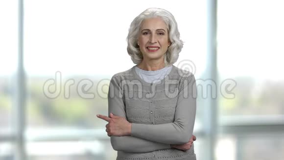 一位老妇人的肖像双手交叉指向左边视频的预览图