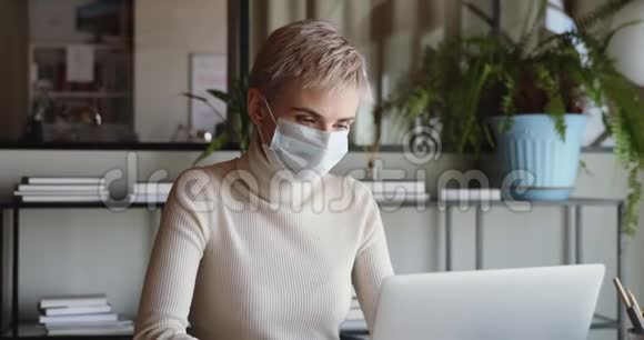 女商人戴着医用口罩和手套在家里办公视频的预览图