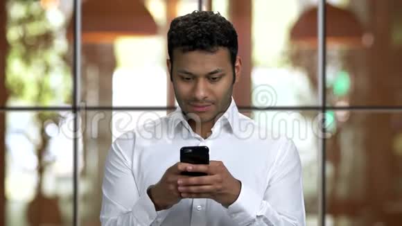 棕色皮肤的印度商人用他的智能手机发短信视频的预览图