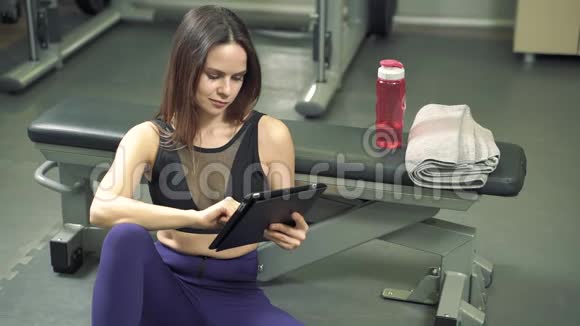 年轻女教练在健身房用平板电脑制定锻炼计划视频的预览图