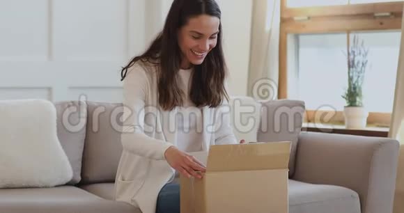 兴奋的年轻女性顾客在家打开包裹盒视频的预览图