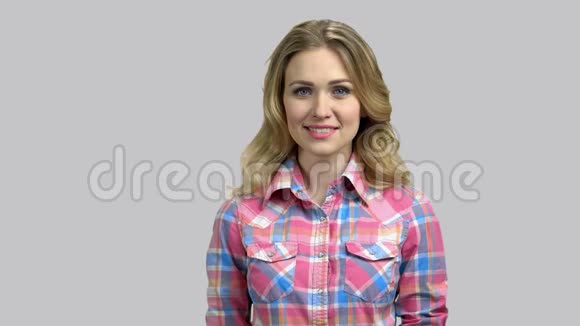 一个年轻的金发女孩带着牙齿高兴地微笑的肖像视频的预览图