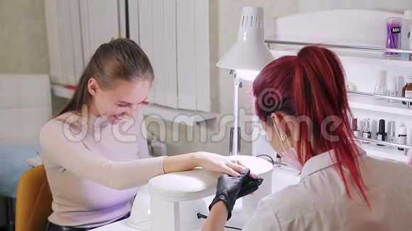 美容院的女美甲师在顾客的指甲上涂上了彩色凝胶抛光剂视频的预览图