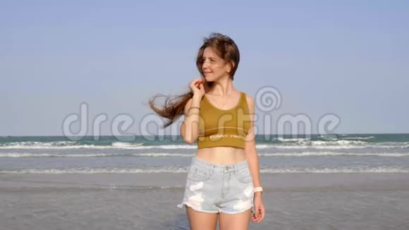年轻漂亮的女人站在海滨背景上有层层波浪视频的预览图