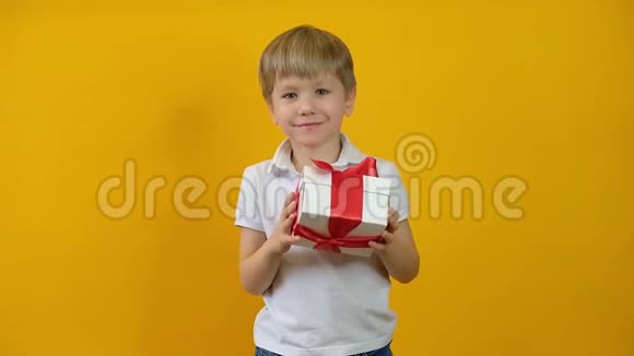 有趣的快乐小男孩蹒跚学步带着黄色背景的礼物微笑视频的预览图