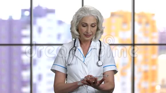 老年女医生使用透明玻璃模型并显示拇指向上视频的预览图
