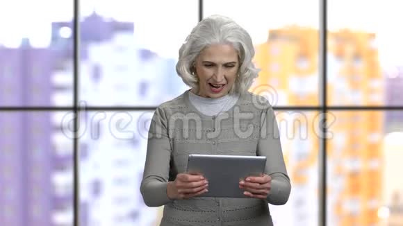 令人兴奋的老奶奶在她的平板电脑上玩游戏视频的预览图