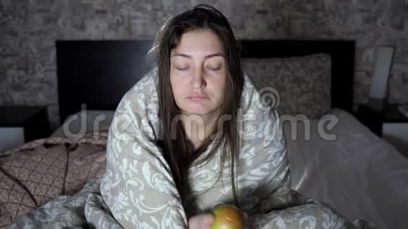 布鲁内特坐在卧室里裹着毯子吃着苹果视频的预览图