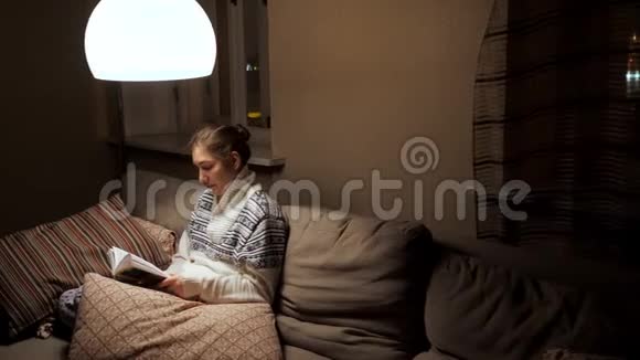 黑发女人晚上读一本书视频的预览图