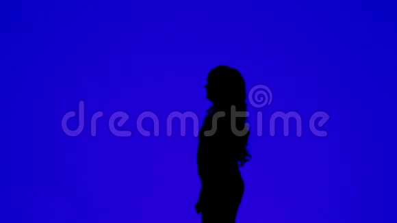 一个卷发的年轻女子在蓝色背景下打电话的剪影视频的预览图