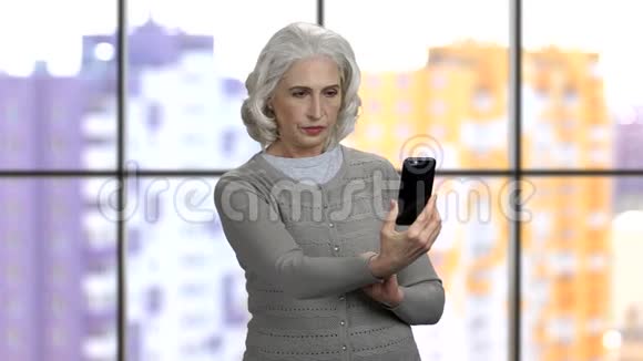 老太太在智能手机相机上拍摄垂直和水平的照片视频的预览图
