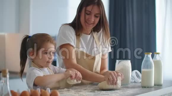 妈妈教女儿慢慢地在厨房里揉面包做饼干妈妈教小女儿学视频的预览图