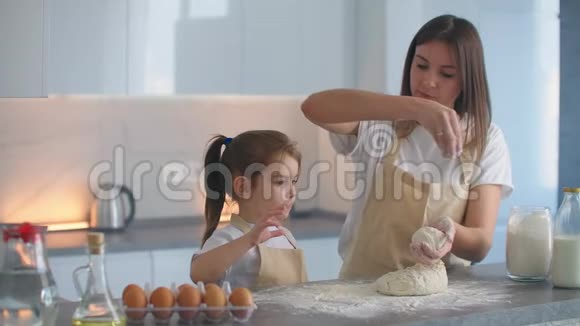 把面粉放在面团上同时用手揉捏和我女儿一起做披萨可爱的母亲视频的预览图