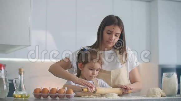 妈妈帮女儿滚面团妈妈和小女儿拿出面团做饼干使用滚针视频的预览图