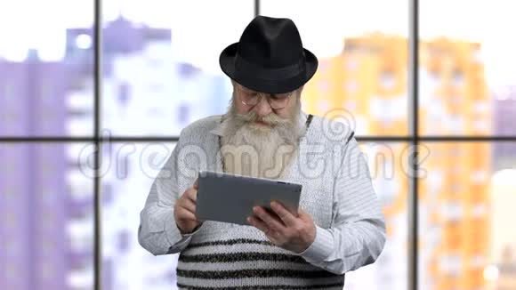 老爷爷在平板电脑上滚动他的社交媒体视频的预览图