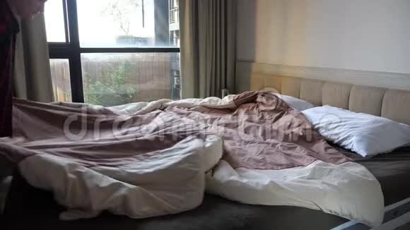 年轻女子用棕色毯子盖大床枕头视频的预览图