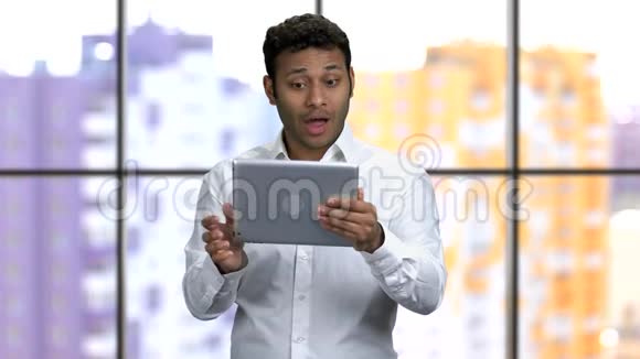 年轻的深色皮肤男人穿着正式的衬衫双手拿着平板电脑视频的预览图